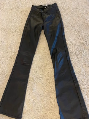 Skin byxor  - Snygga svarta jeans med utsvängda ben och skinnliknande material. Från only. XS L32.   Liten defekt vid fickan men inget som syns