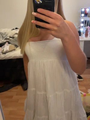 Vit sommarklänning - Säljer en söt vit  klänning med smock upptill och volangig kjol. Klänningen är kort och har en luftig, flowy passform. Klänningen är köpt för några år sedan för gina tricot barnavdelning och gå därför att inte köpa längre(så jag tycker ni borde passa på!) den är i storlek 158/164  och säljs på grund utav att den är för liten för mig. Ett otroligt sommar cap nu till sommaren.