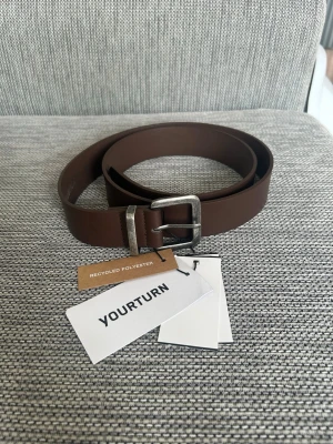 Brunt bälte från YOURTURN - Completely new! Tried it on once at home but it was too big for me & Not real leather. Entire length of the belt: Ca 118cm Hole one: Ca 109cm Hole five: Ca 99cm PS: The belt buckle looks kind of used and a bit dirty but that's just the design, it is completely new and not used at all. If you look it up on Zalando it looks the same there. ❤️