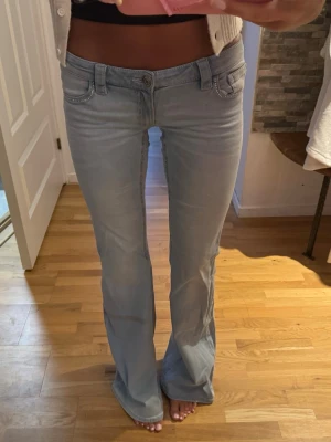Ljusblå bootcut jeans med detaljer - Snygga ljusblå bootcut jeans i tall modell från Gina Young 14+ med dekorativa sömmar och fickdetaljer både fram och bak. Jeansen har låg midja och klassisk femficksdesign. Perfekta för en avslappnad och trendig look. 