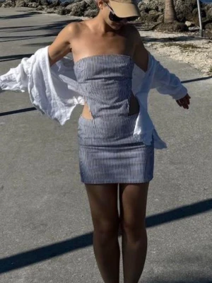 Randig axelbandslös kortklänning - Säljer en snygg axelbandslös kortklänning med smala blåa och vita ränder. Klänningen har cut-out detaljer i midjan och en figurnära passform. Perfekt för varma dagar och sommarens alla äventyr. Men den är tyvärr för liten för mig