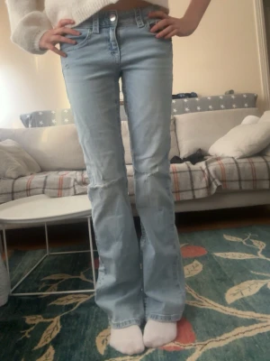Ljusblå bootcut jeans med slitningar str 164 - Säljer dessa jättesnygga fina jeans i storlek 164 med knappar få fickorna och slitningar på knäna. De har ett litet hål vid högra fickan på baksidan, i och med det sänker jag priset men jag tror att det är enkelt att sy ihop💘😋