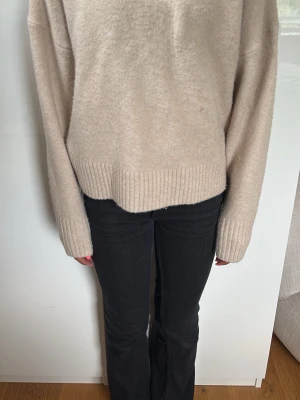 Beige oversized stickad tröja - Mysig beige stickad tröja med oversized passform och långa ärmar. Tröjan har bred ribbstickad mudd vid ärmslut och nederkant. Perfekt för lager på lager och enkel att matcha med olika stilar.