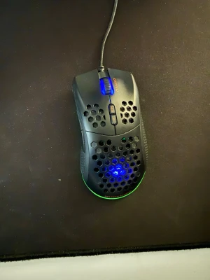 Svart gamingmus med RGB-belysning - Säljer en svart gamingmus från Deltaco Gaming med RGB-belysning och honeycomb-design. Musen har sladd, blått belyst scrollhjul och flera knappar för extra funktioner. Perfekt för gaming och har en lätt och ventilerad konstruktion i plast.