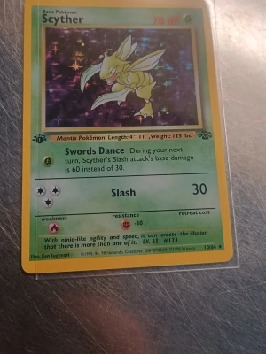 Scyther Jungle 1st Edition  - Säljer ett original Pokémonkort från Jungle-serien, Scyther 10/64. Kortet har en grön och gul ram, med en bild på Scyther mot en mörk bakgrund. Text och symboler i svart och rött. Perfekt för samlare eller nostalgiker!