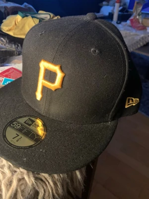 Svart New Era 59FIFTY Pittsburgh Pirates keps - Svart keps från New Era 59FIFTY med Pittsburgh Pirates logga i gult framtill och broderad New Era-logga på sidan. Aldrig använd