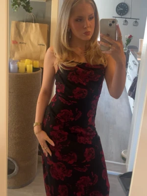 Svart långklänning med röda blommor - Säljer en snygg svart långklänning med röda blommor från Gina Tricot i storlek 36. Klänningen har smala axelband och har en figurnära passform som framhäver siluetten. Perfekt när man vill klä upp sig och känna sig extra fin. Bara använd 1 gång. Nypris 600kr. Skriv vid funderingar eller för fler bilder🥰