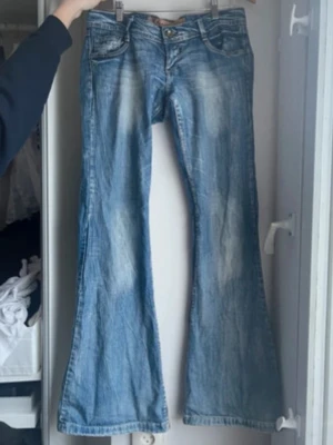 Blå bootcut jeans - (köpta för 1200)Säljer ett par blå bootcut jeans och tvättade detaljer. Jeansen har klassiska fem fickor och låg midja. Materialet är denim i bomull och passformen är utsvängd nedtill för en retro vibe.