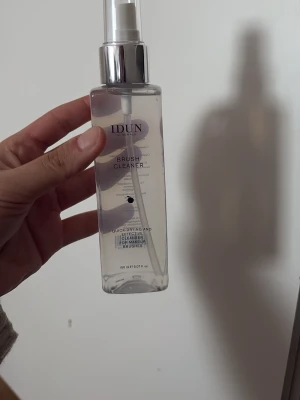 IDUN Brush Cleaner spray 150 ml - Transparent sprayflaska med silverfärgad pump från IDUN Minerals. Innehåller 150 ml snabbtorkande rengöring för makeupborstar. Flaskan är rektangulär och tillverkad i plast. Perfekt för att hålla borstar fräscha och hygieniska. Helt oanvänd!