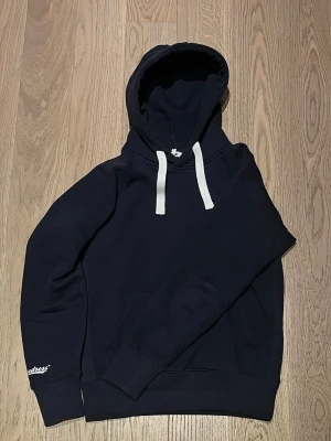 Russemerch Hoodie - Marinblå Russemerch Hoodie i storlek Medium. Tröjan är i väldigt gott skick.