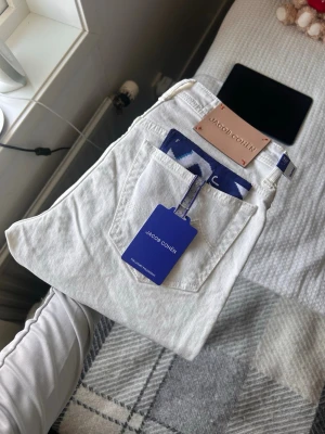 Vita jeans från Jacob Cohën - Snygga vita jeans från Jacob Cohën med klassisk femficksmodell och raka ben. Jeansen har detaljer som logotyp-patch bak och blå etikett. Tillverkade i ett mjukt denimtyg som känns lyxigt och fräscht.