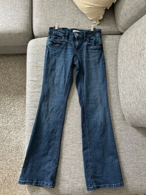 Mörkblå bootcut jeans  - Snygga mörkblå jeans med bootcut-modell. Jeansen har fem fickor, justerbar midja och är tillverkade i mjuk denim med lite stretch. Perfekta för dig som gillar en avslappnad men trendig look. Storleken är 164 men dom är som xs/s då det går och justera i midjan