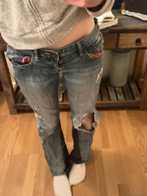 Lågmidjade jeans - Lågmidjade jeans med hål och lite slitningar, säljer för dom inte passar mig. Har sytt in dom lite i midjan vilket syns på sista bilden. Midje mått = 38 Innerbenslängd = 80