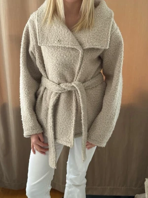 Beige teddyjacka med knytskärp - Mysig beige teddyjacka med bred krage och knytskärp i midjan. Håller värmen ganska bra så passar både vinter, vår och höst💖 Från Gina Tricot💖💖 
