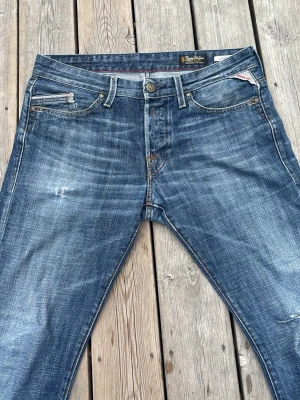 Blå raka jeans från Replay - Säljer ett par klassiska blå jeans från Replay med raka ben och slitningar för en cool, avslappnad look. W31 L34