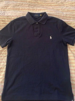 Marinblå piké från Polo Ralph Lauren - Parfekt för dig som är runt 180-190 cm den är slim fit å Parfekt nu för sommaren. Säljer på grund av att den är för lång å nästan alldrig använd 
