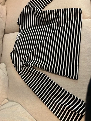Svartvit randig långärmad topp från NA-KD - Snygg långärmad topp med svartvita ränder och rund hals. Tillverkad i mjuk bomull som känns skön mot huden. Perfekt att styla med jeans eller kjol för en trendig look. Tröjan är från NA-KD