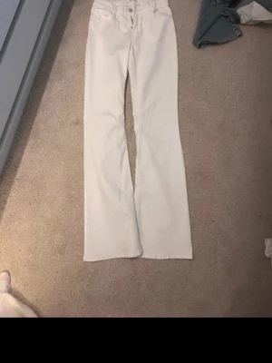 Vita low waist bootcut jeans - Snygga vita bootcut jeans med klassisk femficksdesign. Jeansen har en lätt utsvängd passform nertill och är tillverkade i ett mjukt denimtyg som ger en skön känsla. Perfekta för dig som vill ha en stilren och trendig look. Storlek 170 men är som en xs