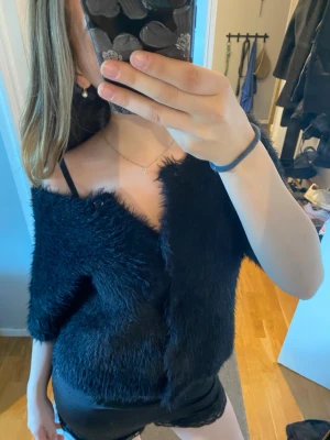 Svart fluffig stickad kofta - Säljer en svart stickad kofta med fluffig textur och kortare ärmar. Tröjan är från Wera och är i storlek xs men sitter bra på mig med s-m