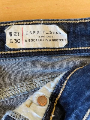 Bootcut jeans från Esprit Denim - Mörkblå bootcut jeans från Esprit Denim med klassisk knappgylf och kontrastsömmar. Jeansen har en snygg passform med utsvängda ben (bootcut).super comfortable om du vill ha något mysigt men ändå stilig. Den är dessutom low waist med en snygg fram ficka. Passa på!