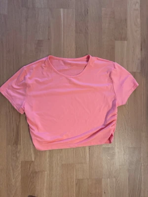 Rosa croppad t-shirt - En enkel och stilren rosa croppad t-shirt med rund halsringning och korta ärmar. Perfekt till jeans eller kjol för en avslappnad look. Tillverkad i mjukt material som känns skönt mot huden.