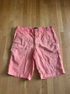 Morris shorts - Snygga Morris korallrosa shorts med klassisk passform och raka ben. Shortsen har sidofickor fram och två bakfickor med knappdetalj. Perfekta för sommaren. storlek 28. Ca en S