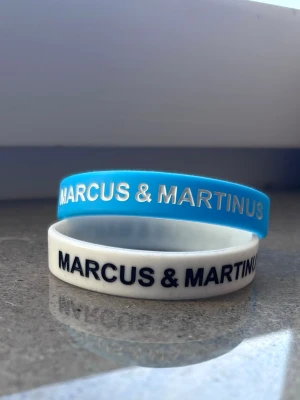 Marcus & Martinus armband - Två coola armband med Marcus & Martinus-tryck, ett i blått med vit text och ett i vitt med svart. Skriv gärna innan ni trycker på köp då annonsen ligger ute på flera ställen🫶🏻