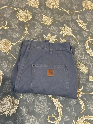 Grå cargobyxor från Carhartt - Snygga grå cargobyxor från Carhartt med klassisk patch på bakfickan. Byxorna har flera praktiska fickor och robusta sömmar. Perfekta för en avslappnad streetwear-look. Tillverkade i slitstarkt bomullstyg.