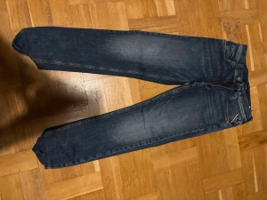 Replay jeans - Säljer ett par mörkblå jeans med raka ben och klassisk femficksmodell. Jeansen har en snygg tvätt med lätt slitning och kontrastsömmar. Materialet är denim i bomull. Perfekta till en avslappnad stil.