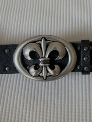 Rockstar Fleur Belt - Bold Fleur de Lis design on a clean black belt. 100 cm strap, 3.7 cm width. Silver buckle 8 × 5.8 cm. 