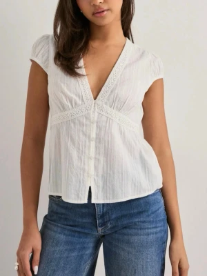 Vit blus med spetsdetaljer - Säljer en vit blus med v-ringning och dekorativa spetsdetaljer längs halsen. Kortärmad och luftig design som är perfekt för varma dagar. Aldrig använd och helt ny🥰