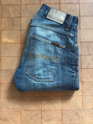 Nudie selvedge grim Tim - Säljer dessa riktigt feta Nudie selvedge i modellen grim Tim. De är storlek 28/32 men upplagda till 100cm (w30). Litet hål i vänstra knät, skriv vid frågor eller funderingar 