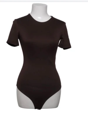 Mörkbrun basic body med kort ärm - En stilren mörkbrun body med korta ärmar och rund halsringning. Tight passform som framhäver figuren och knäppning i grenen. Perfekt att styla till både jeans och kjol. Bodyn är ifrån amisu i st Xs verkligen superfin💕prislapp finns även på ifrån Sellpy 