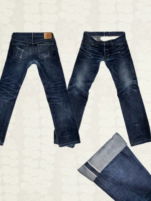 15oz Selvedge Japan Blue Jeans - Selvedge Japan Blue Jeans 15oz. Regular fit. Grymt snygga slitningar som såklart kommit över tid, skräddare har lagat hål runt grenen. Tag size 32/35 (passar mer som en strl 30/32, Mått (cm): Midja: 41 Ytterbenslängd: 102 Lår: 29 Fotvidd: 18.5) Pris kan diskuteras. Hör av dig vid frågor!