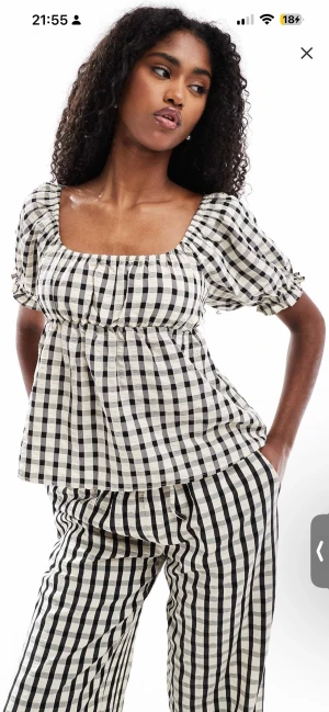 Rutig blus med puffärm och öppen rygg - Supersöt rutig blus i svart och vitt med puffärmar och fyrkantig ringning. Toppen har en öppen rygg med knyt och resår vid ärmslut. 