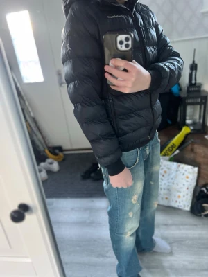 Svart dunjacka från Peak Performance - Säljer en svart dunjacka från Peak Performance med huva och dragkedja framtill. Jackan har en puffig design, ribbade muddar vid ärmsluten och två sidofickor med dragkedja. Perfekt för kalla vinterdagar och riktigt snygg till jeans.