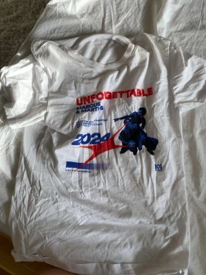Vit t-shirt Unforgettable 2024 - Vit t-shirt med tryck framtill från Marcus & Martinus. Stort färgglatt motiv med texten 'UNFORGETTABLE 2024' och en bild på artisterna. Klassisk passform och rund halsringning. Perfekt för fans som vill sticka ut.