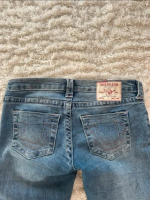 Blå True Religion jeans bootcut - säljer mina true religon jeans då de är lite stora för mig❤️ de är i storlek 26 o skulle säga att de är ungefär S. har lånat bilderna från den jag köpte de av! de är väldigt slitna då jag gått på de! därför de e ute ganska billigt och hör av dig om du vill ha bild på det slitna så löser jag det!❤️ de är rosa på fickorna och sömmarna!