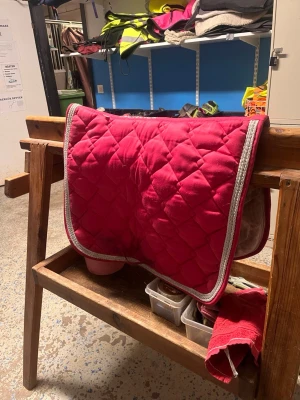 Rosa schabrak med glittrig  kant - Säljer ett snyggt rosa schabrak med vit och grå kant. Perfekt till hästutrustningen, ger en färgklick till din ridning. Schabraket har klassisk rektangulär form och är tillverkat i mjukt, vadderat material. Storlek full❤️