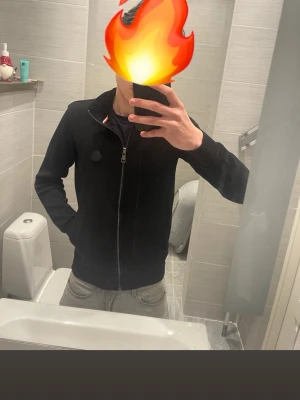 Moncler kofta - Säljer en svart Moncler kofta med silver dragkedja och hög krage. Koftan har en diskret patch på bröstet och är långärmad. Perfekt för dig som gillar en clean och enkel stil. Passar till det mesta och är riktigt skön att bära. Den är av bra material tjockt och fint, Storlek S. Skriv ifall du har någon fråga!😁🤝