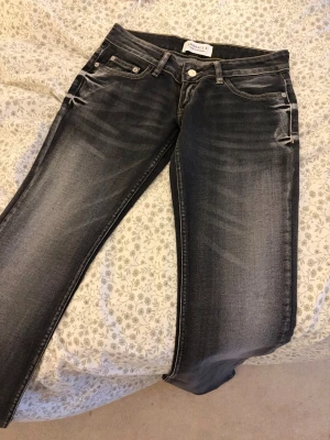 Svarta low rise jeans från Embrace K - Snygga svarta low rise jeans från Embrace K med slitningar och tvättade detaljer. Jeansen har klassisk femficksmodell, normalhög midja och stretchigt denimtyg för skön passform. Perfekta till en avslappnad och trendig look.