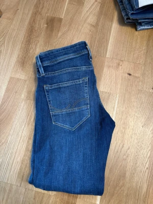 Jack and Jones slim jeans - Snygga mörkblå jeans med klassisk femficksdesign och raka ben. Jeansen har kontrastsömmar och en enkel bakficka med diskret broderi. Perfekta för en avslappnad och stilren look.