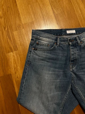 Blå raka jeans från Tiger of Sweden - Snygga blå jeans från Tiger of Sweden med klassisk femficksmodell och raka ben. Jeansen har en tvättad look med subtila slitningar och är tillverkade i bomull. Perfekta för en avslappnad och stilren outfit. Helt nya då dem inte passade mig.
