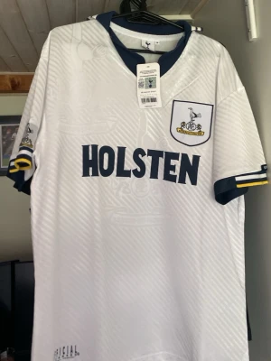 Tottenham Hotspur retro matchtröja från 94/95 - Vit retro matchtröja från Tottenham Hotspur med mörkblå detaljer, klubbmärke på bröstet och HOLSTEN-tryck på framsidan. Helt ny o aldrig använd med etikett kvar men säljer den för den är för stor👍