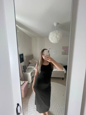 Svart ärmlös långklänning - En stilren svart långklänning med ärmlös design och rund halsringning. Klänningen har en figurnära passform och är perfekt för dig som gillar en enkel men snygg look. Passar till sneakers eller klackar beroende på humör.