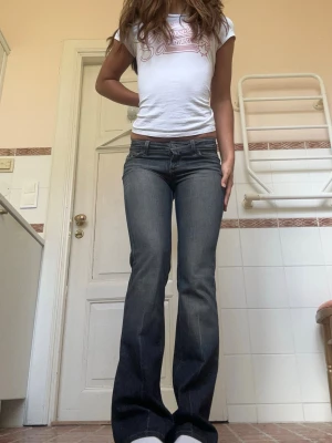 Paige lowwaist blå 2000s bootcut jeans - ❣️Strl W26 men passar W25 lika väl!!❣️Säljer ett par mörkblå lågmidjade jeans från Paige med snygga broderade detaljer på bakfickorna. Jeansen har låg midja och klassisk femficksmodell. Materialet är stretchigt denim som sitter bekvämt och formar sig efter kroppen. Perfekta för en trendig och avslappnad look. Sitter som en smäck!