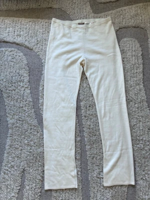 Krämvita smala mjukisbyxor från H&M - Mysiga vita smala mjukisbyxor från H&M. Byxorna har en rak passform med slits i slutet av benen och är tillverkade i ett mjukt och stretchigt material som passar perfekt för chill hemma. Resår i midjan för extra komfort.