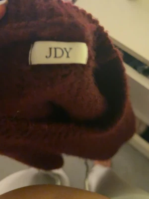 Vinröd stickad tröja från JDY - Mysig vinröd stickad tröja från JDY med korta ärmar och avslappnad passform. Perfekt för lager-på-lager och enkel att styla med både jeans och mjukisbyxor. Tröjan har en klassisk rund halsringning och är i ett mjukt material.