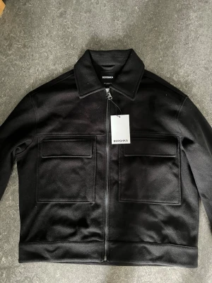 Jacka från Bershka, Overshirt.  - Helt oanvänd Jacka från Berskha i Storlek M (Svart overshirt) En riktig fräsch och billig jacka som du kan nästan använda när du vill och är perfekt för kvällar och är en riktig mode overshirt. Priset kan även diskuteras. 