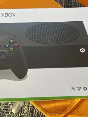 Xbox Series S 1TB med svart handkontroll - Xbox Series S spelkonsol i svart med tillhörande svart trådlös handkontroll. Konsolen har 1TB SSD-lagring och stöd för upp till 120 FPS. Modern och stilren design i plast med rund ventilationsyta på ovansidan. Har väldigt bra skick jätte bra för TV-Spel t.ex FIFA kan köras väldigt bra o smidigt. Finns inga skador eller problem med konsolen.